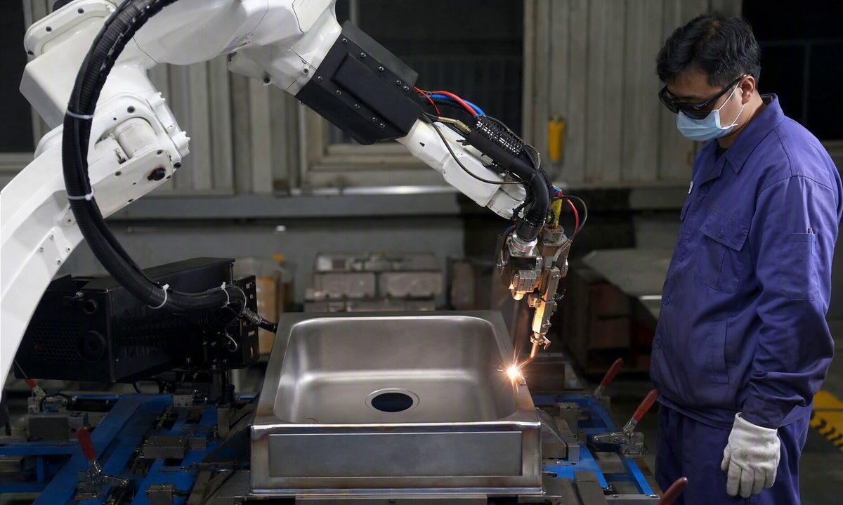 Robotic arm welding a stainless steel sink